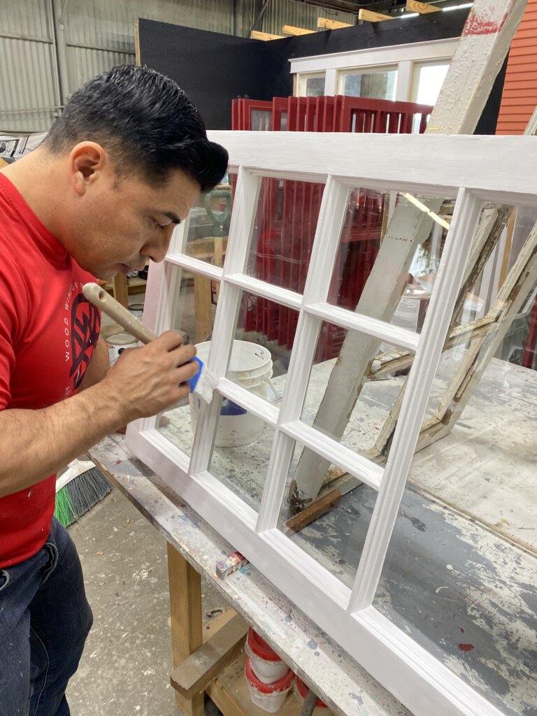 Painter applying a paint finish on this divided lite casement sash